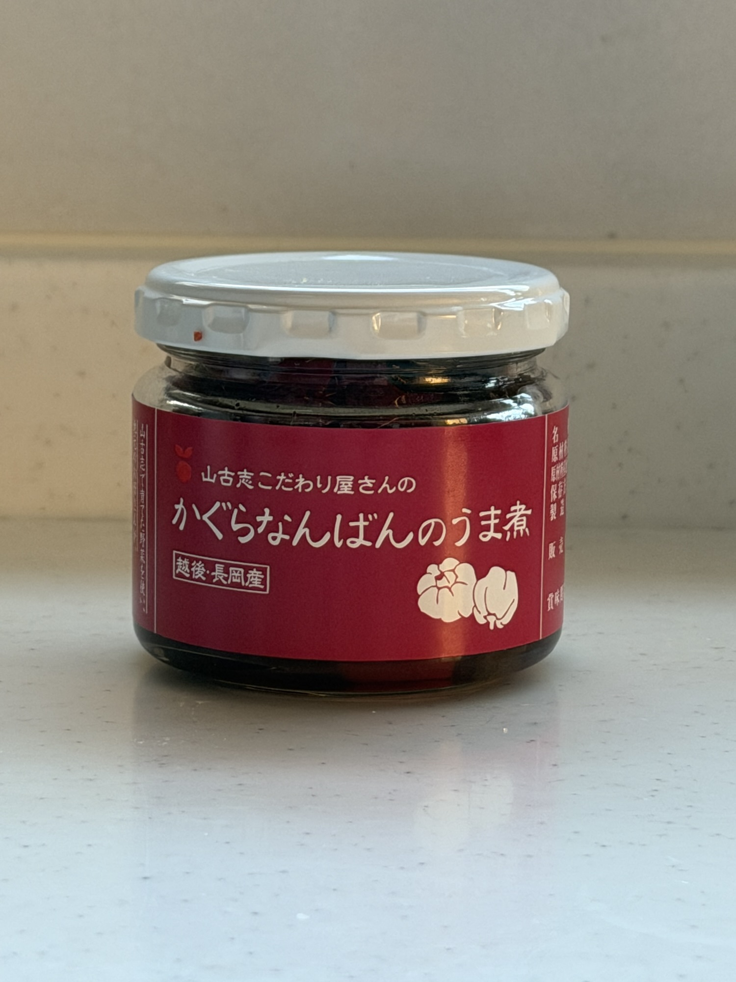 山古志こだわり屋さんの「かぐらなんばんのうま煮」越後・長岡産の瓶詰めパッケージ表面。赤いラベルが目印