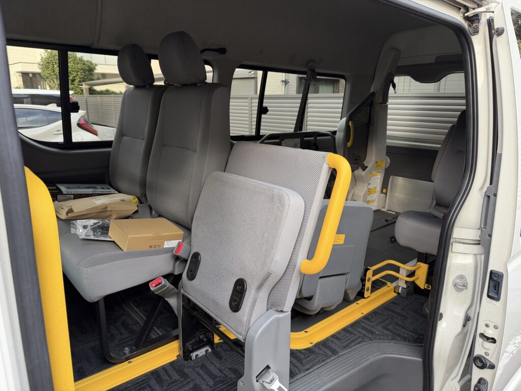 ハイエース ウェルキャブの車内。後席に車椅子用スペースと黄色いグリップ・電動リフトが見える福祉車両仕様