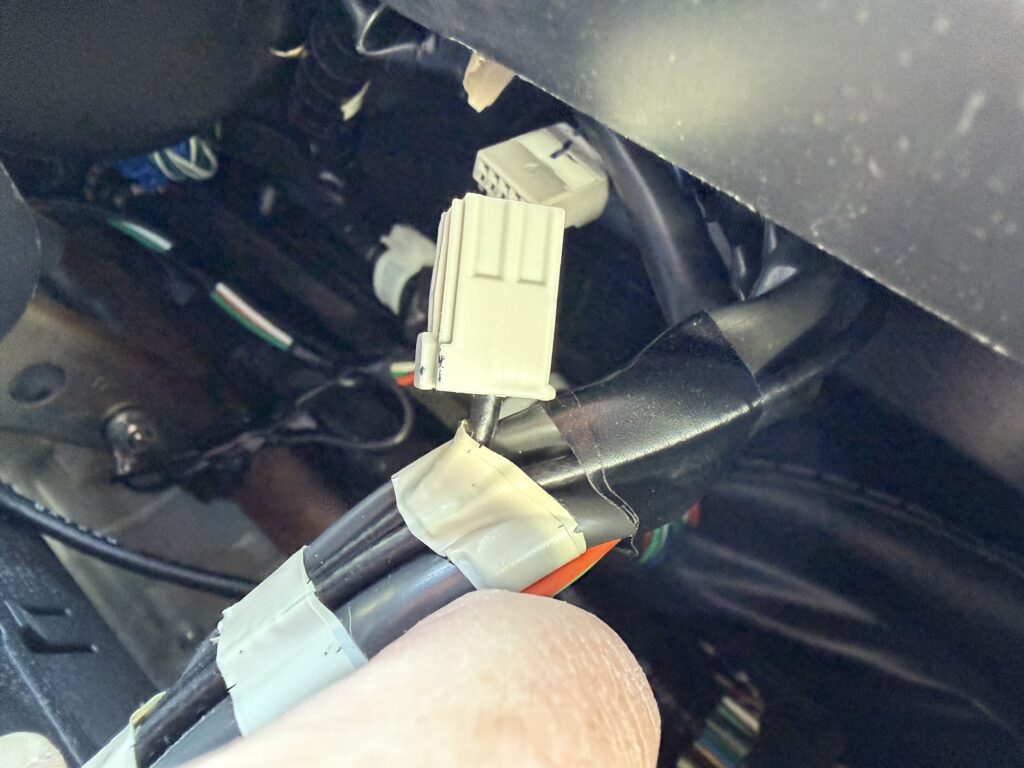 車内ピラー裏で配線コネクターを接続している作業中の手元