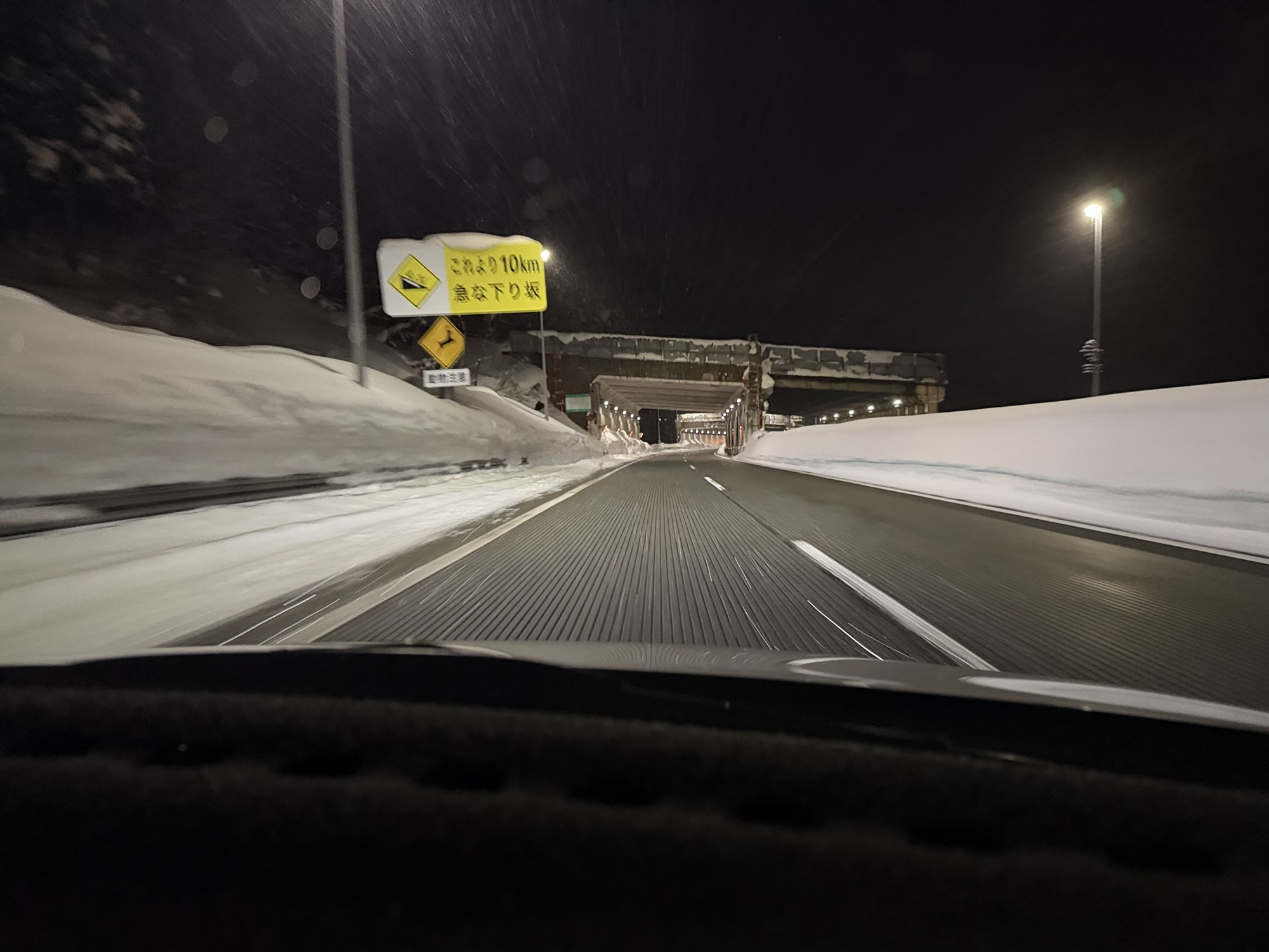 土樽PAから湯沢IC方面の高速道路。スノーシェッドと急な下り坂の警告標識