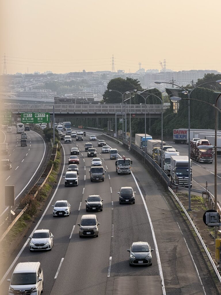 東名川崎・東京500m地点の標識と大型車が並ぶ駐車エリア